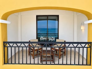 A balcony with a table and chairs, a view of the ocean, and a yellow wall. - Hotel Bello Veracruz (Boca del Río)