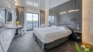 Una habitación de hotel moderna con una cama grande, un baño con espejo y vistas al exterior.