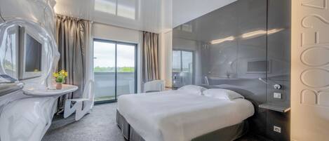 Una habitación de hotel moderna con una cama grande, un baño con espejo y vistas al exterior.