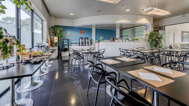 A modern cafe with black bar stools, a counter with a coffee machine, and a large window with a view. - Comfort Aparthotel Bassin d'Arcachon (La Teste-de-Buch)