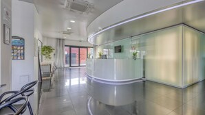 A modern reception area with a curved reception desk, glass partitions, and a clean, reflective floor. - Comfort Aparthotel Bassin d'Arcachon (La Teste-de-Buch)