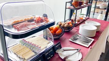 A buffet with various food items, including cheese, meats, fruits, and condiments.