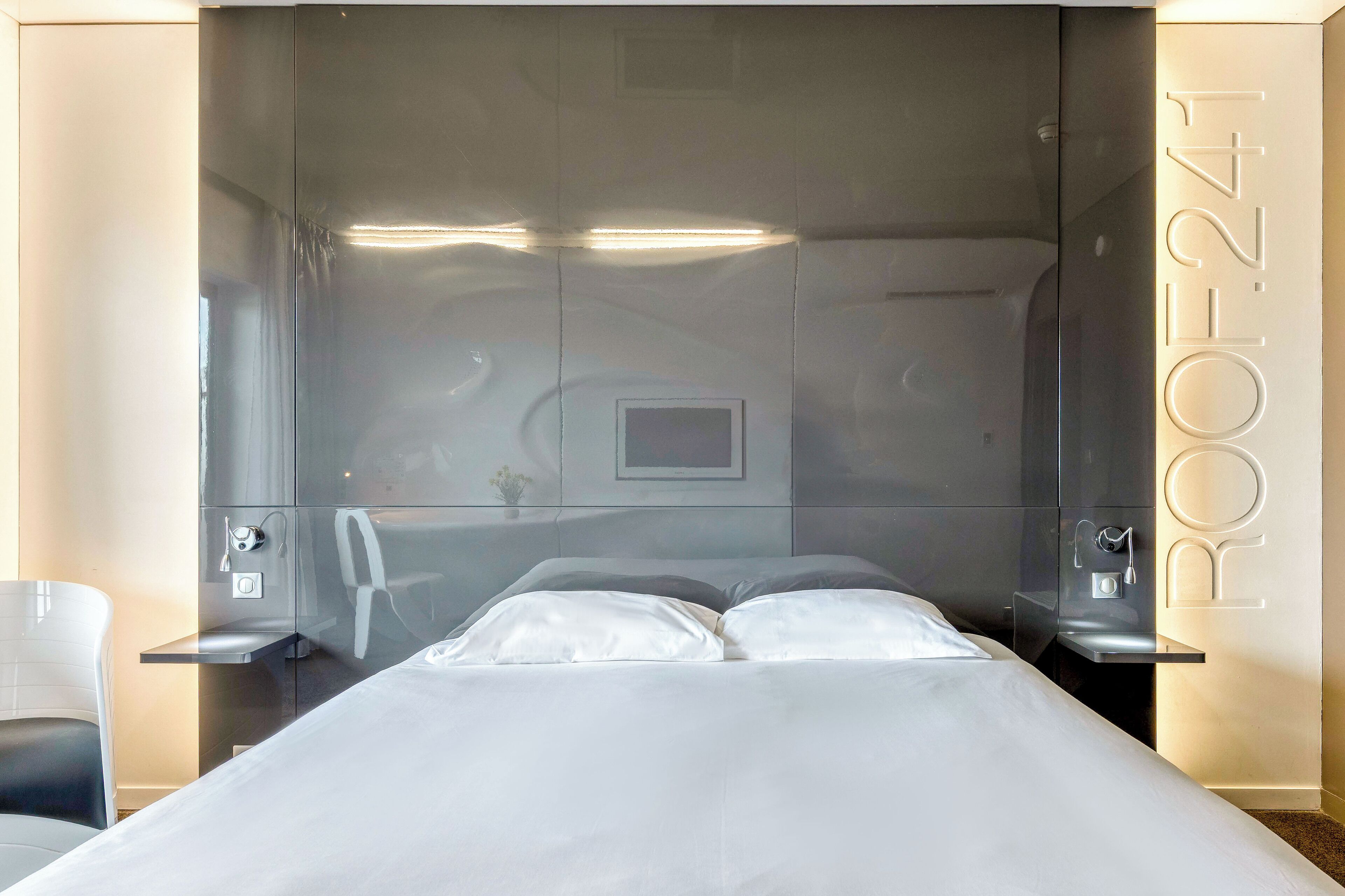 Une chambre d’hôtel moderne avec un grand lit, une table de chevet et un petit bureau.