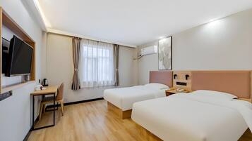 Una habitación de hotel con cama, escritorio con silla, televisor y ventana con cortinas.