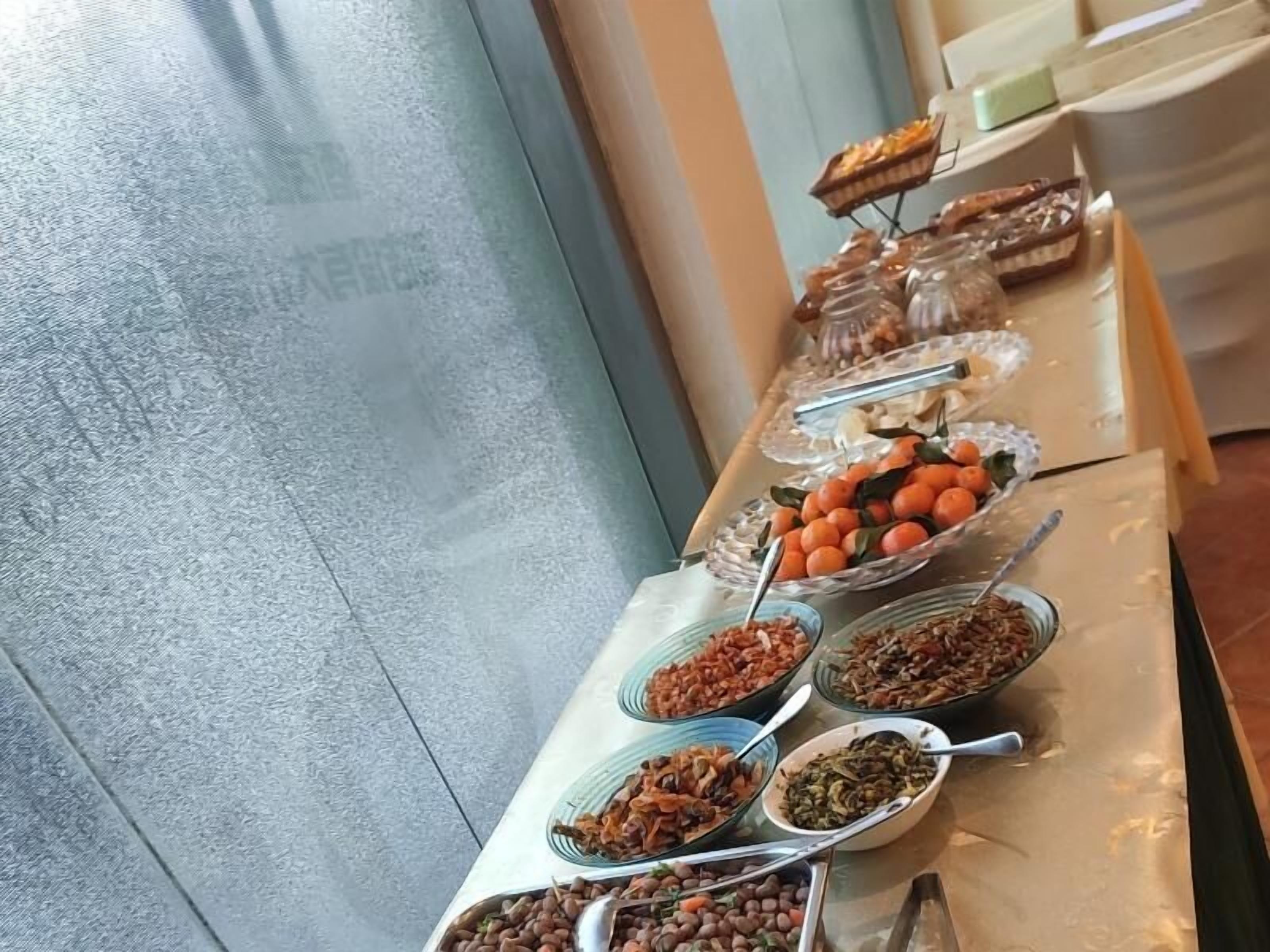A buffet table with various food items including fruits, nuts, and other snacks.