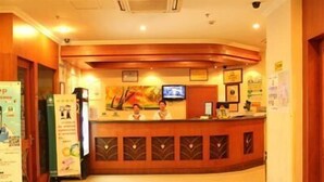 A hotel reception area with a wooden reception desk, a flat-screen TV, and a large poster on the wall. - Greentree Inn Yancheng Dafeng Hotel (Yancheng)