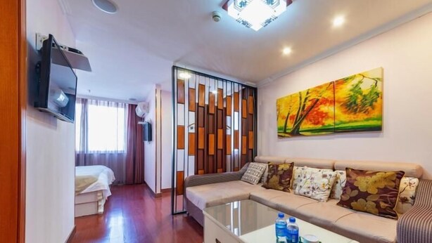 A modern living room with a sofa, a coffee table, and a painting on the wall. - Greentree Inn Yancheng Dafeng Hotel (Yancheng)