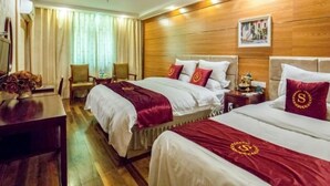 A hotel room with two beds, wooden flooring, a desk with a vase, and a window with curtains. - GreenTree Inn Shanghai Chongming Bao Town Express Hotel (Shanghai)