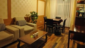 A hotel room with a sofa set, a dining table with chairs, a coffee table, and a potted plant. - GreenTree Inn Shanghai Chongming Bao Town Express Hotel (Shanghai)