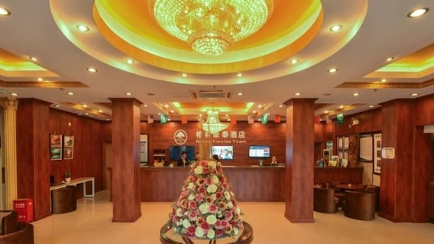 A hotel lobby with a reception desk, a chandelier, and a floral arrangement on a pedestal. - GreenTree Inn Shanghai Chongming Bao Town Express Hotel (Shanghai)