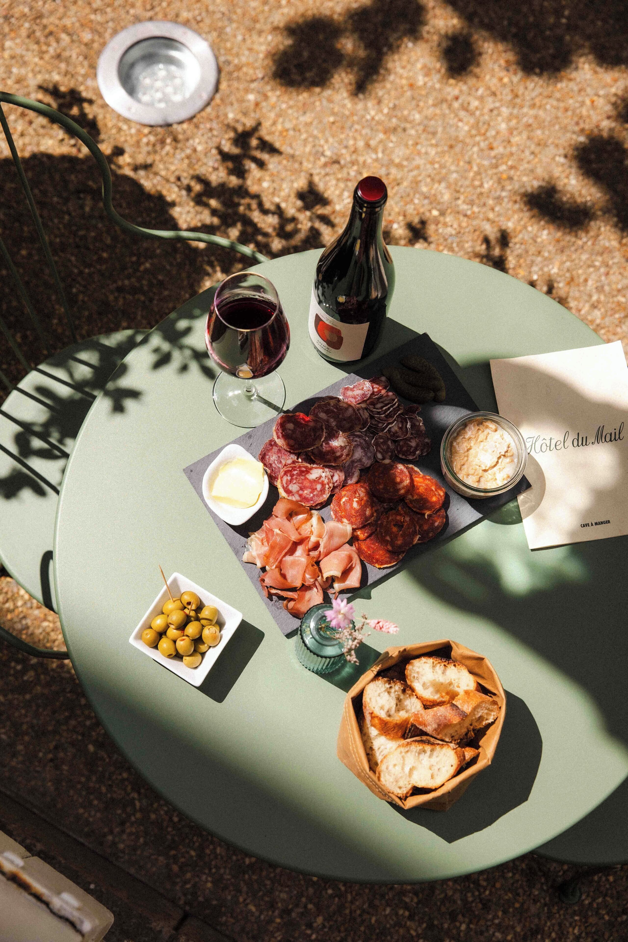A round table with a variety of food items including cheese, olives, bread, and a bottle of wine.