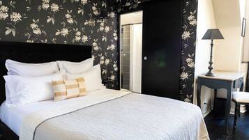 Un dormitorio con cama, almohadas, un escritorio y una silla.