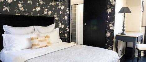 A bedroom with a bed, pillows, a desk, and a chair.