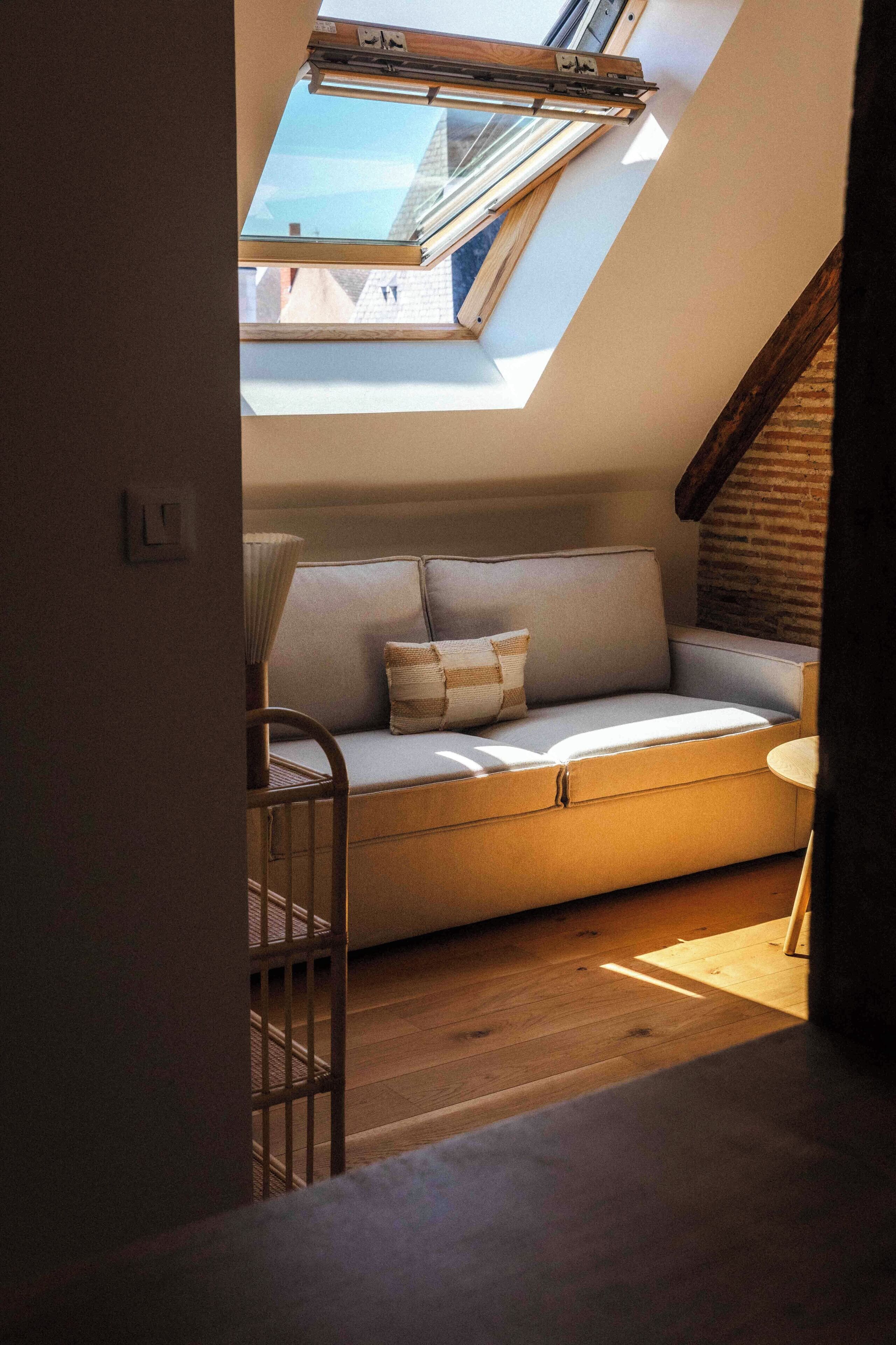 Una habitación acogedora con techo inclinado, sofá empotrado y tragaluz.
