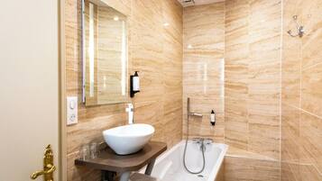 A modern bathroom with a marble wall, a white sink, and a bathtub.