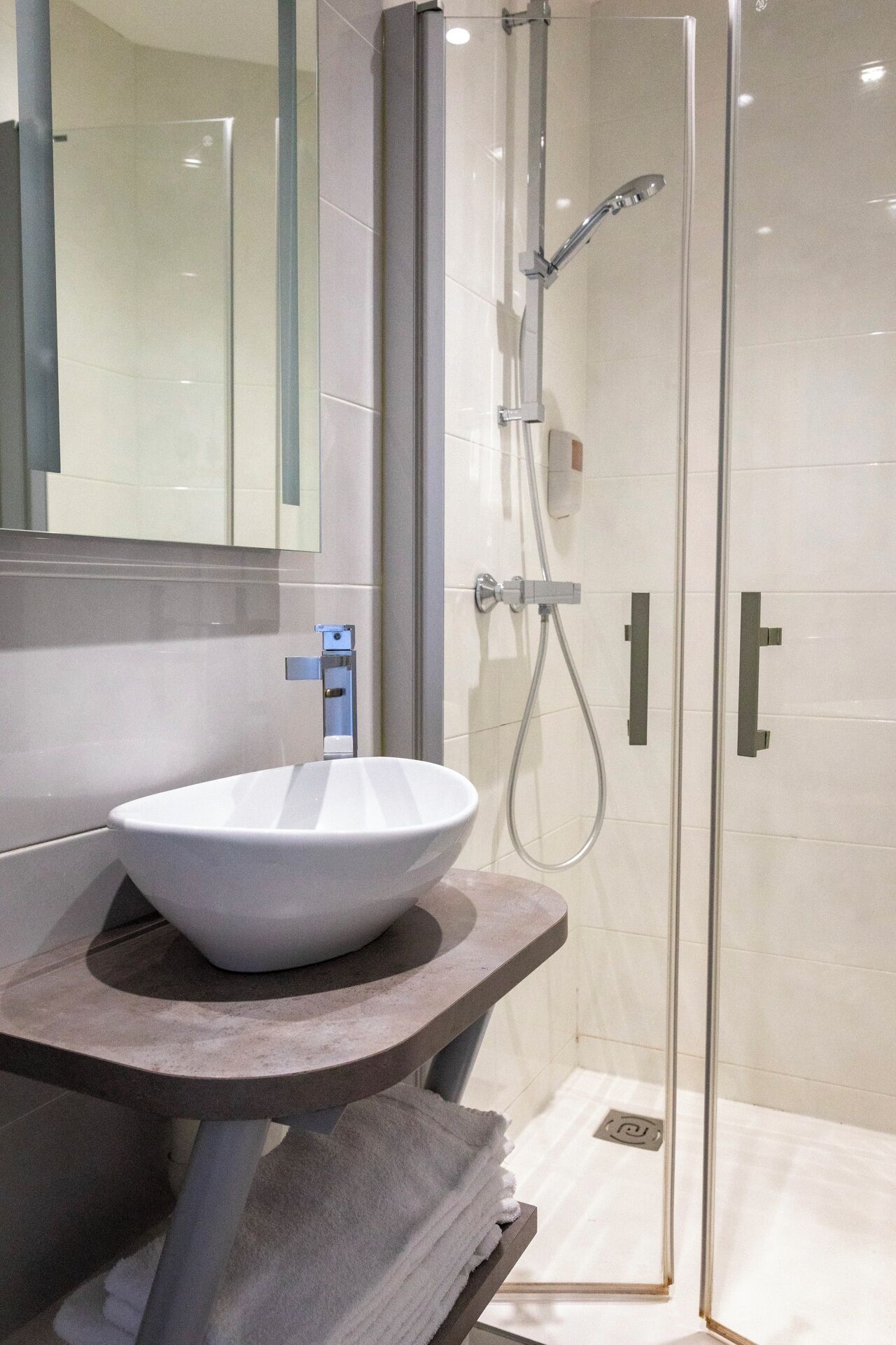 Une salle de bain moderne avec un lavabo blanc, une douche à parois de verre et un grand miroir.