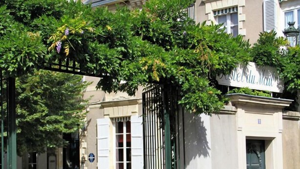 Un bâtiment sur lequel on peut lire l’inscription « Hôtel du Mail », doté d’une entrée fermée par un portail et d’une cour intérieure pavée.