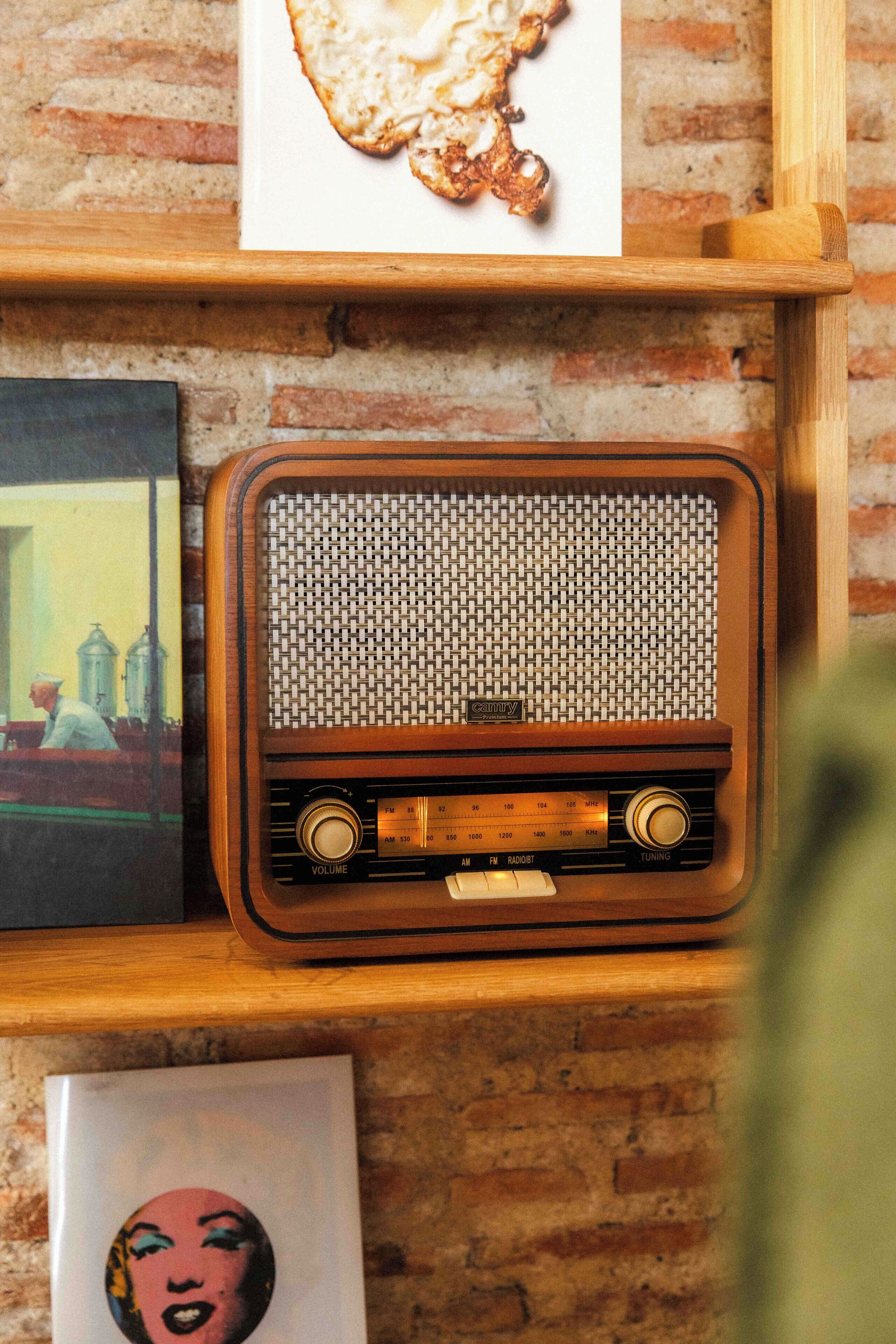 A wooden shelf with a vintage radio, a framed picture of a woman, and a framed artwork.
