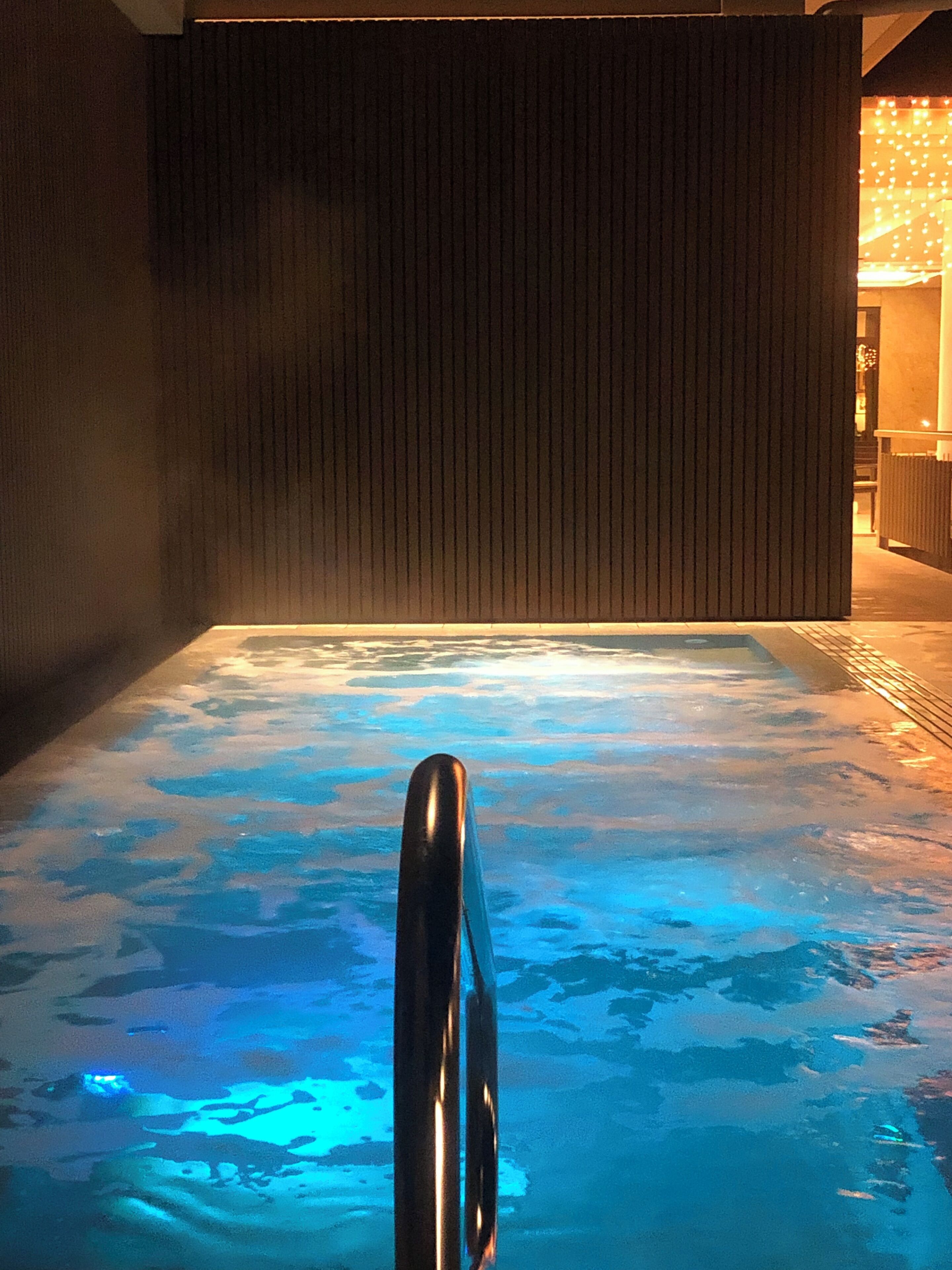 A hot tub with a wooden wall in the background.