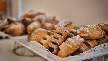 A tray of assorted pastries, including croissants and other baked goods, arranged on a white plate.