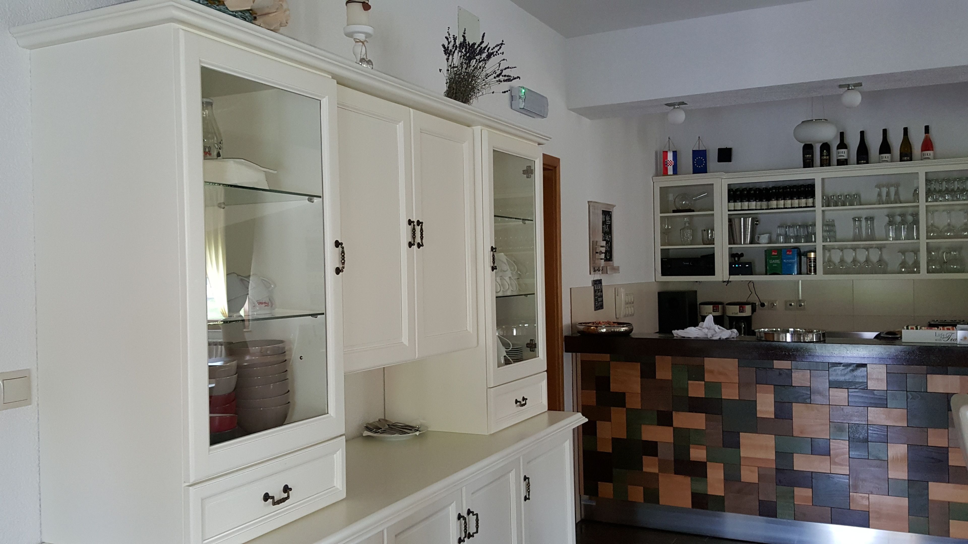 A kitchen with white cabinets, a tiled backsplash, and a variety of kitchenware.