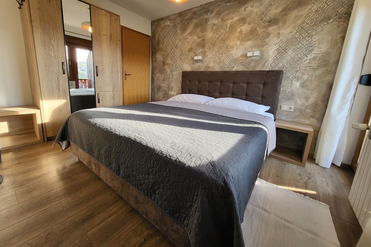 A bedroom with a bed, wooden wardrobe, and a textured wall.