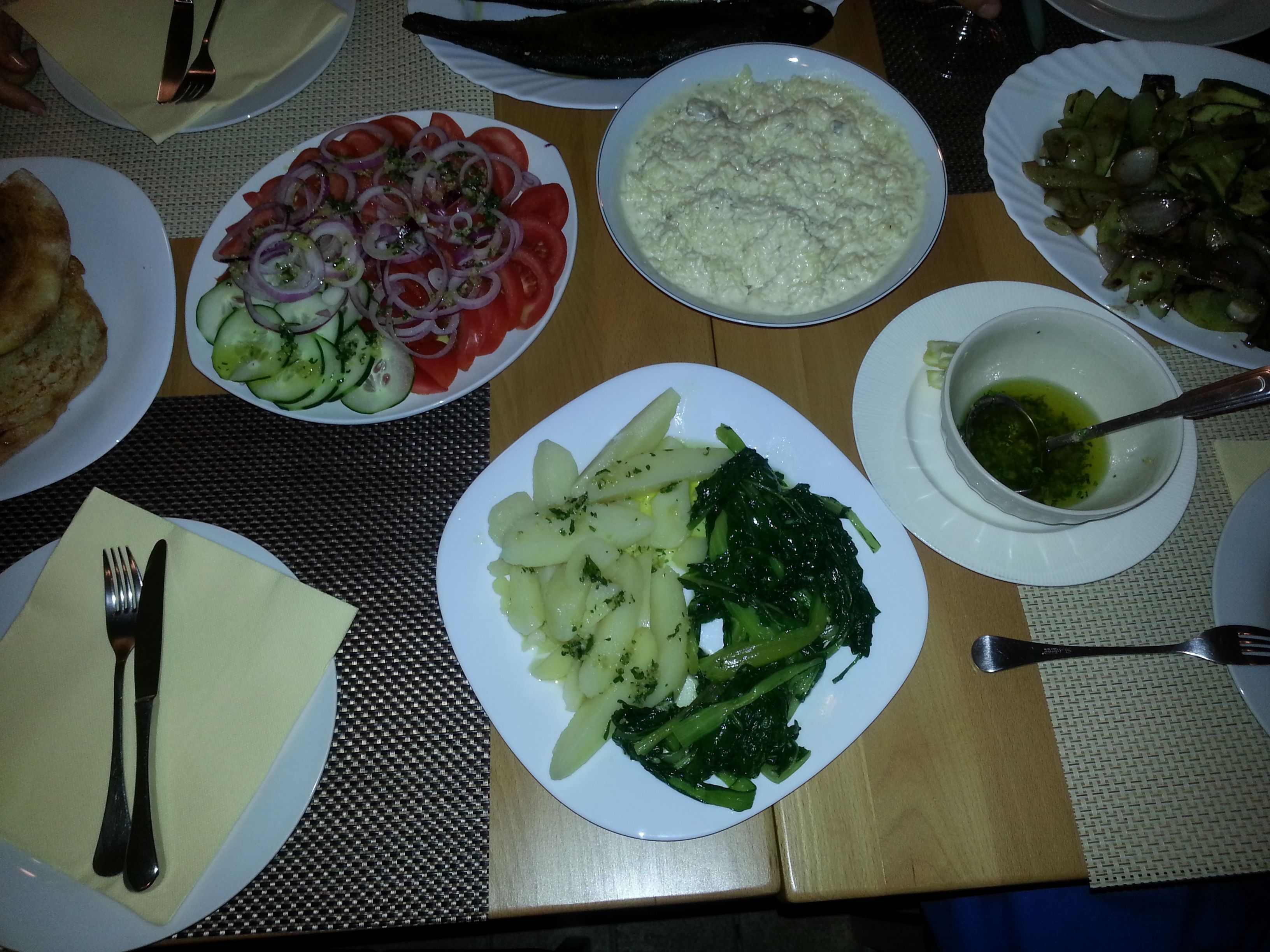 Una mesa dispuesta con diversos platos, entre ellos una ensalada, patatas y un bol de sopa.