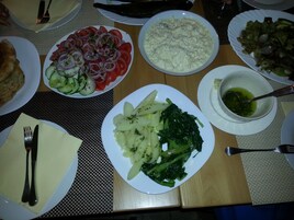Una mesa dispuesta con diversos platos, entre ellos una ensalada, patatas y un bol de sopa.