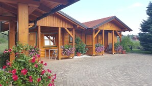 A wooden cabin with a tiled roof, a covered porch, and a paved driveway. - House Tina - Bed and Breakfast (Rakovica)