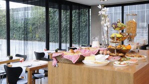 A breakfast buffet with various food items and a large window with a view of trees.