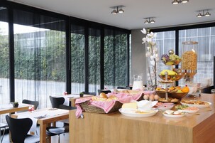 A breakfast buffet with various food items and a large window with a view of trees.