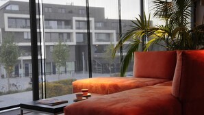 A modern living room with a large window, a sofa, a small table, and a potted plant.