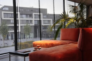 A modern living room with a large window, a sofa, a small table, and a potted plant.