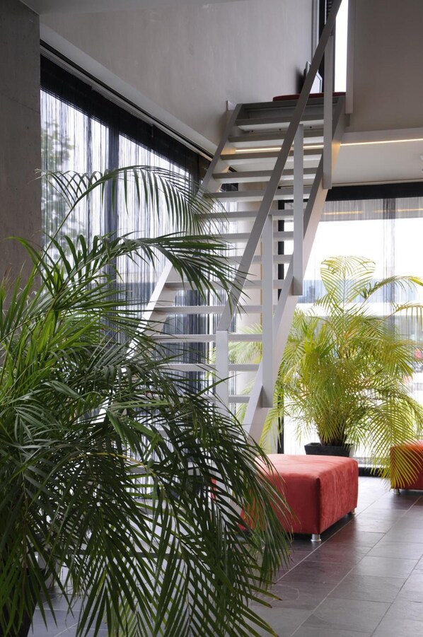 A modern interior with a staircase, large windows, and indoor plants.
