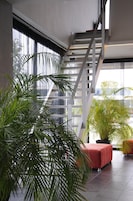 A modern interior with a staircase, large windows, and indoor plants.