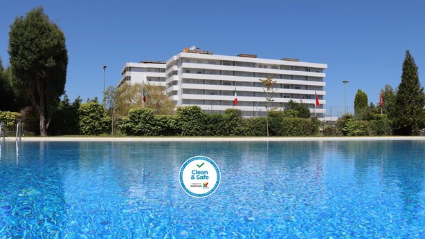 Un hotel con piscina, immerso nel verde sotto un cielo azzurro.