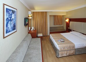 A hotel room with two beds, a sofa, a desk with a lamp, and a painting on the wall. - Julian Club Hotel - All Inclusive (Marmaris)