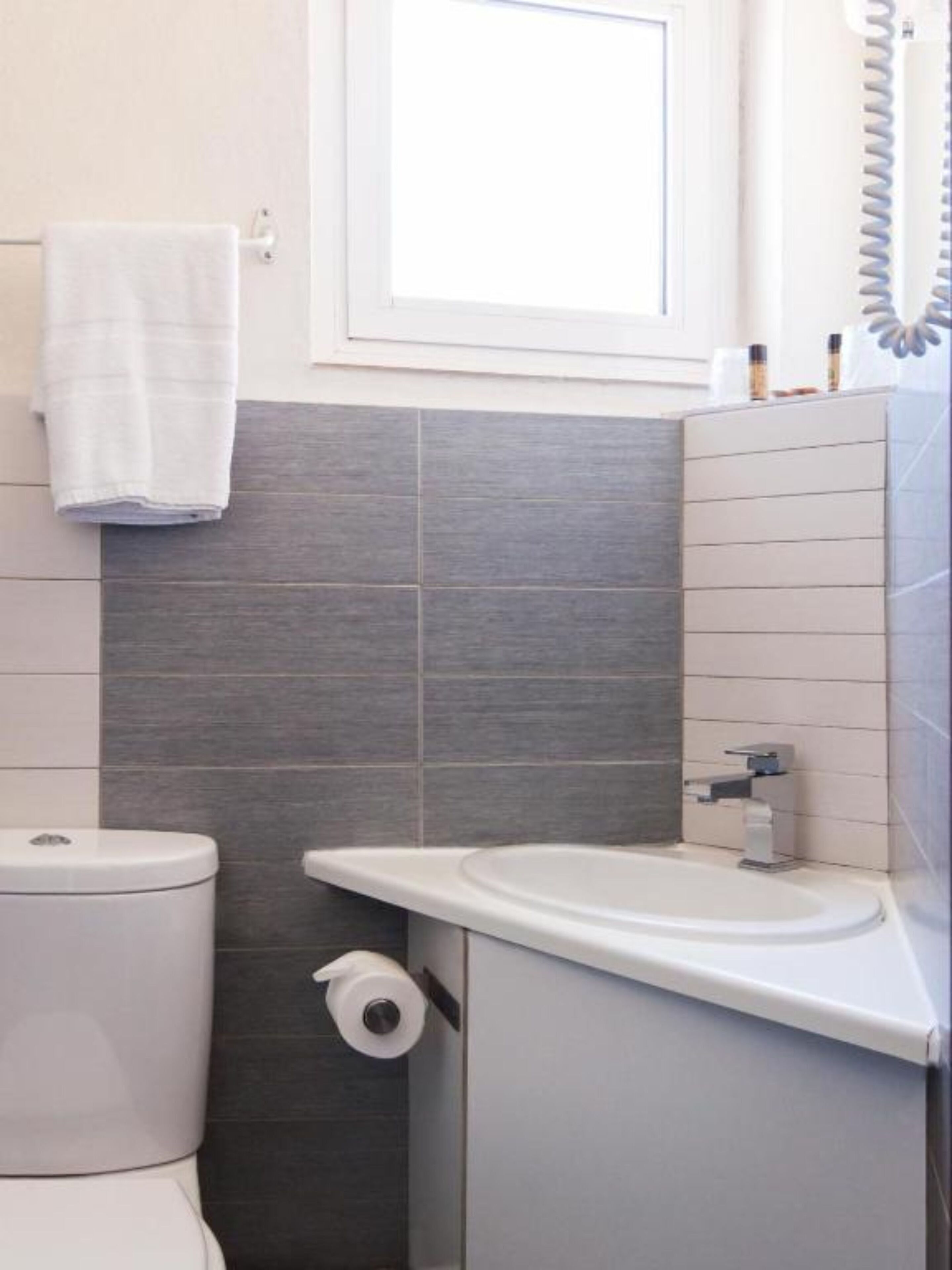 Ein modernes Badezimmer mit Toilette, Waschbecken und einem Handtuch an der Wand.