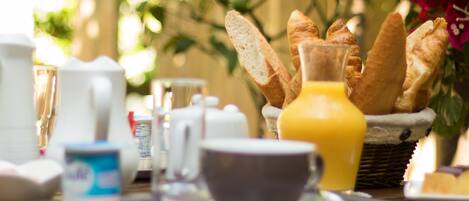 A breakfast table with bread, a jug of orange juice, and a cup.
