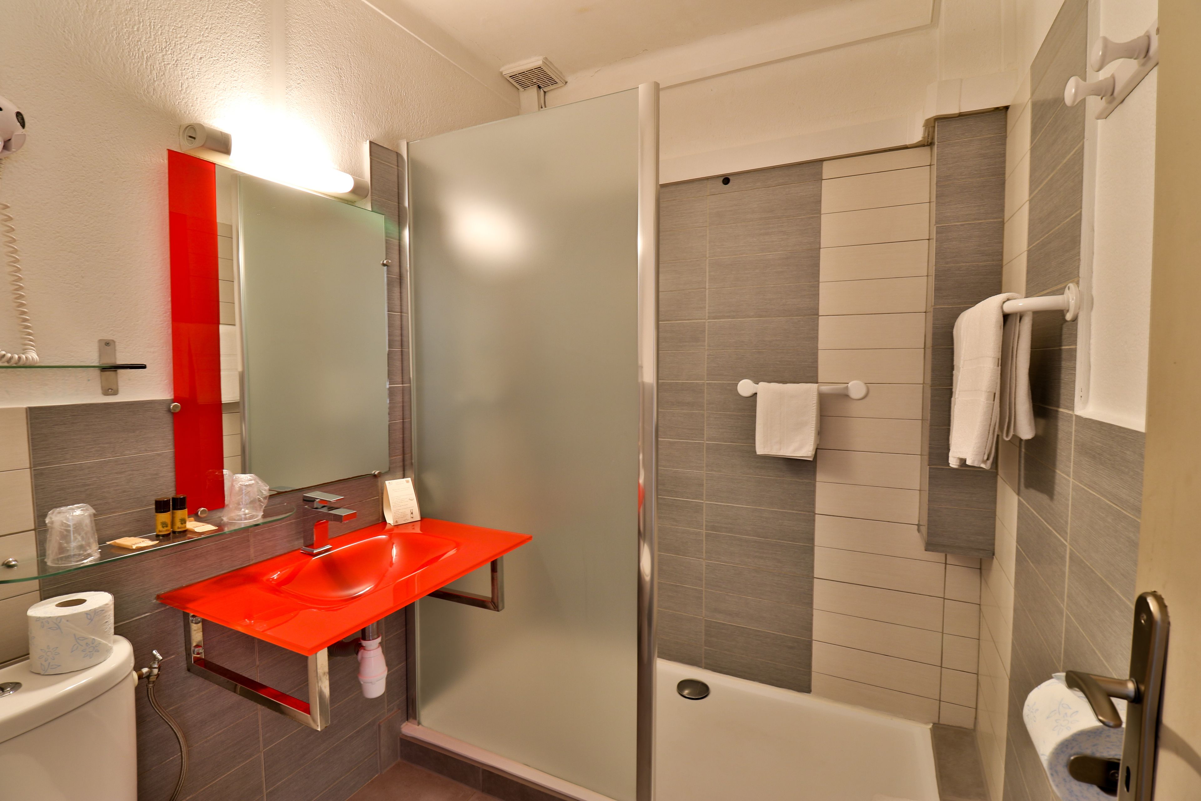 Une salle de bain moderne avec un lavabo en verre, une douche et une baignoire.
