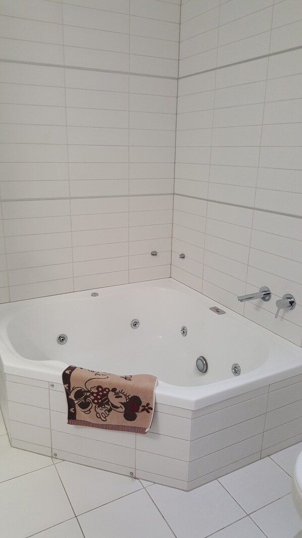 Une salle de bain d’angle avec une baignoire sur pieds, une serviette et des toilettes.