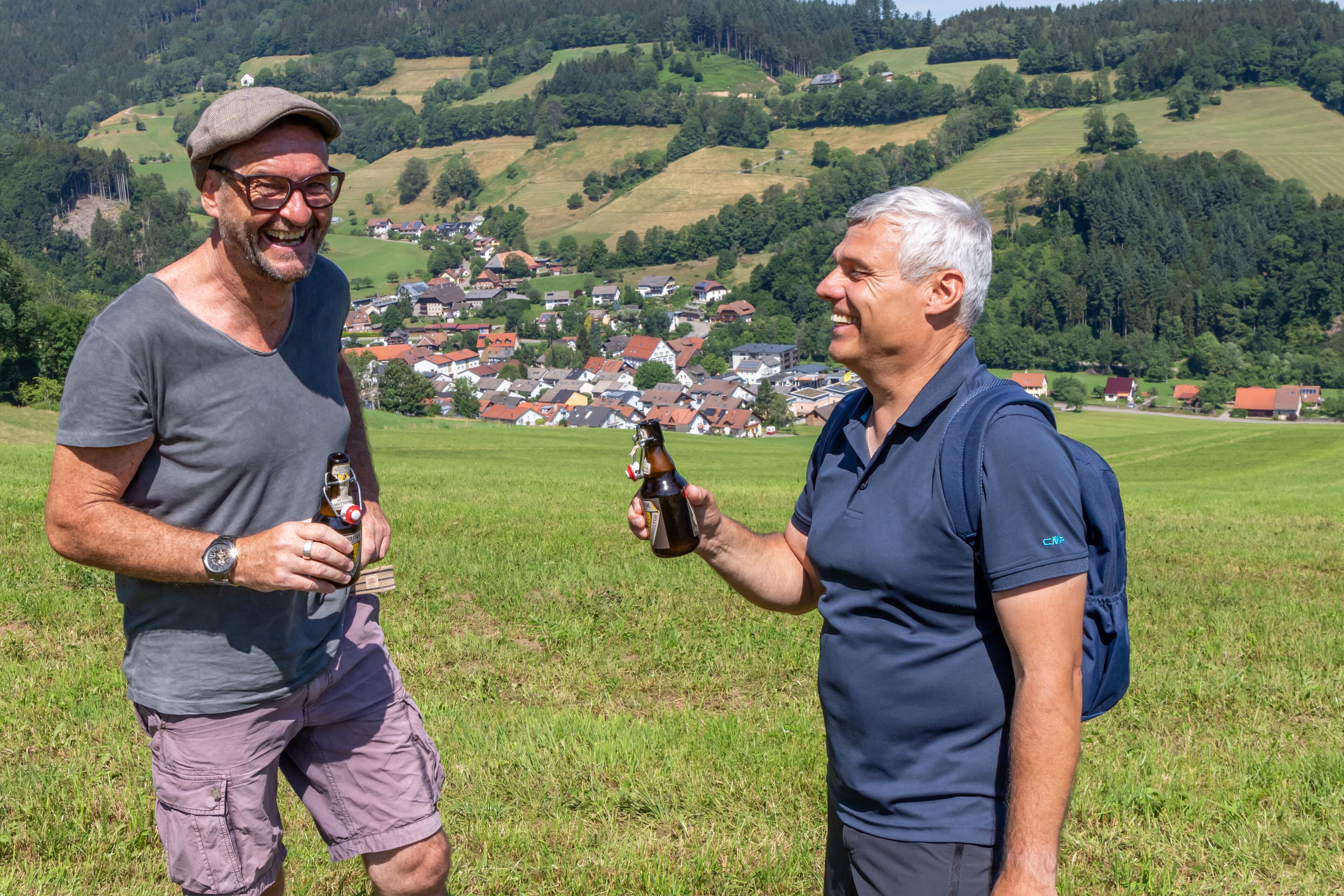 Two men in a grassy field with a village in the background.