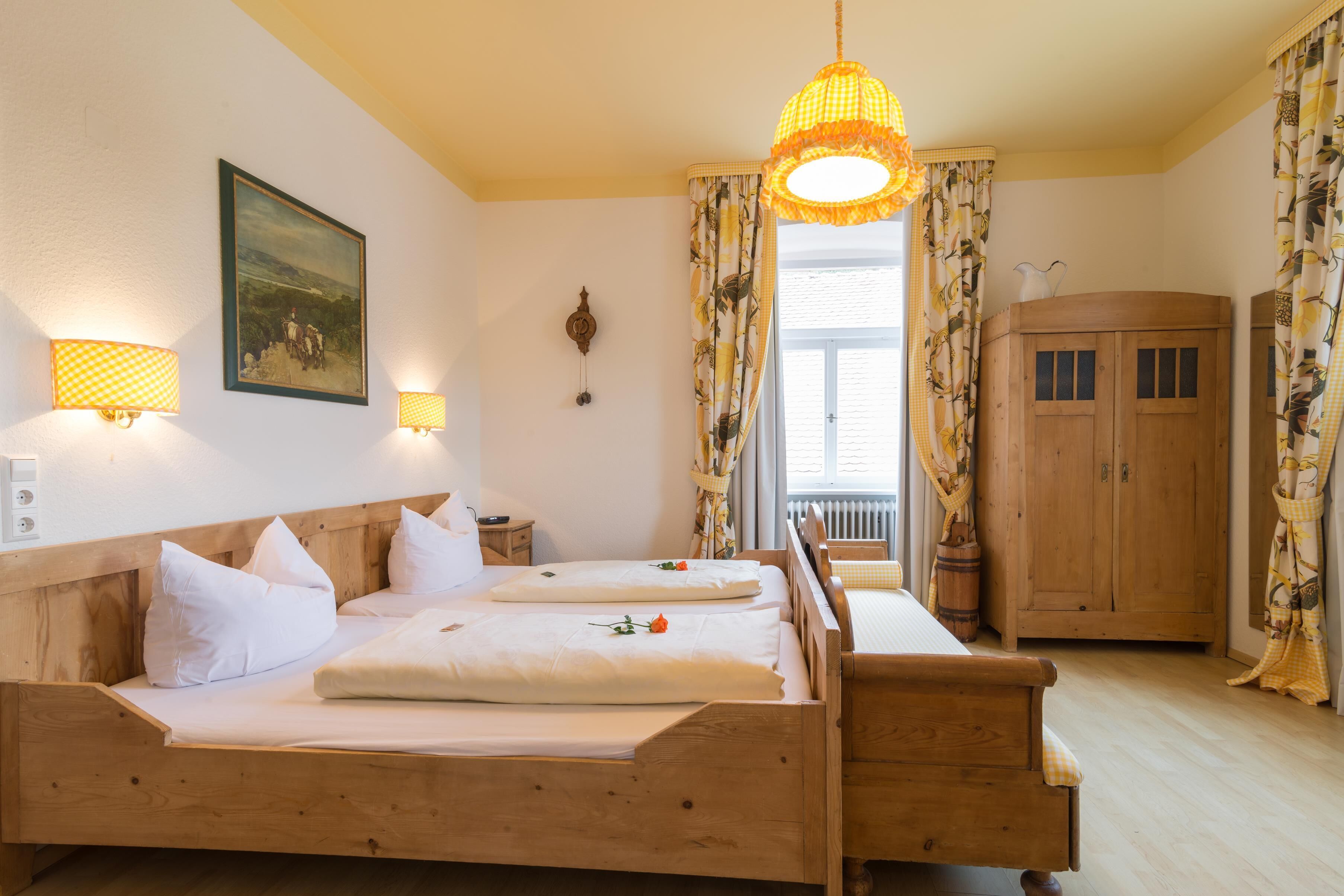 A double bed with white linens, a wooden headboard, and a hanging light fixture.