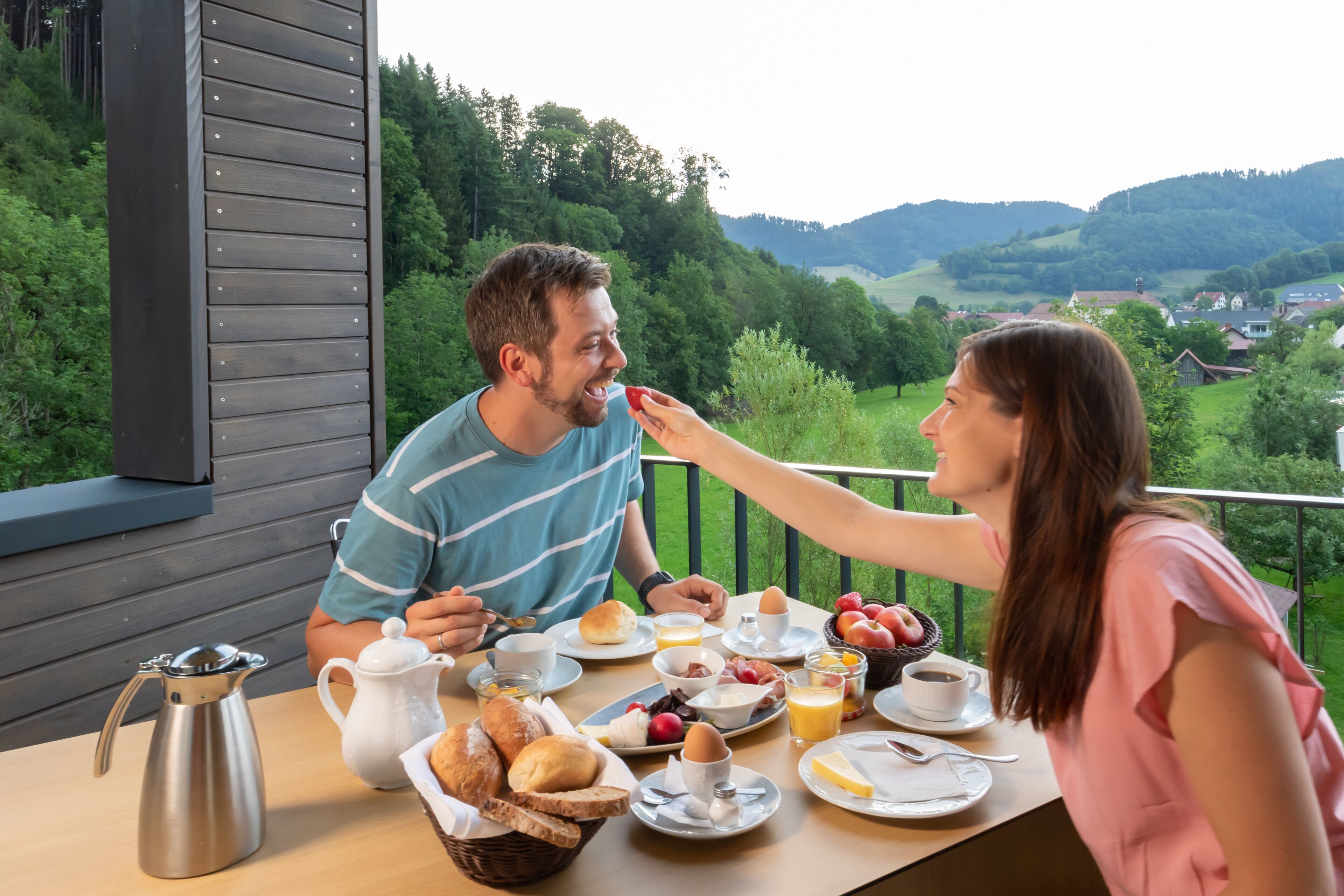 Un tavolo da pranzo con prodotti per la colazione e vista su un paesaggio verde.