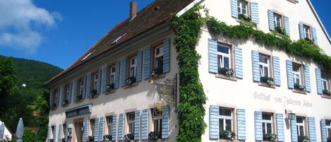 Un edificio tradicional con fachada blanca y contraventanas azules, que muestra un letrero que dice "Gasthof zum Goldenen Adler".