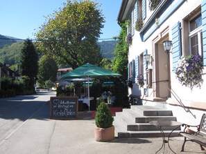 A restaurant with outdoor seating, a chalkboard sign, and a mountain backdrop. - Goldener Adler Oberried - Hotel & Appartements (Oberried)