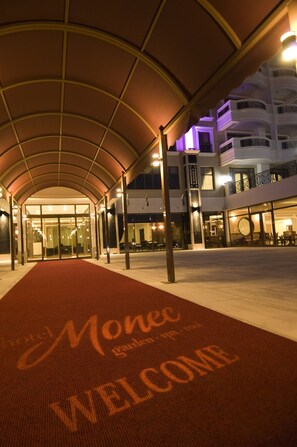 A hotel entrance with a red carpet and a 'Welcome' sign.