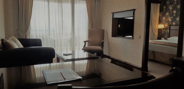A hotel room with a bed, a chair, a desk with a lamp, and a TV. - Hotel Monec (Ankara)