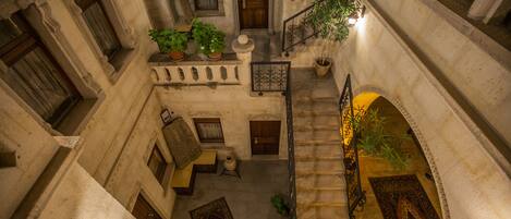A courtyard with a staircase, potted plants, and a patterned rug.