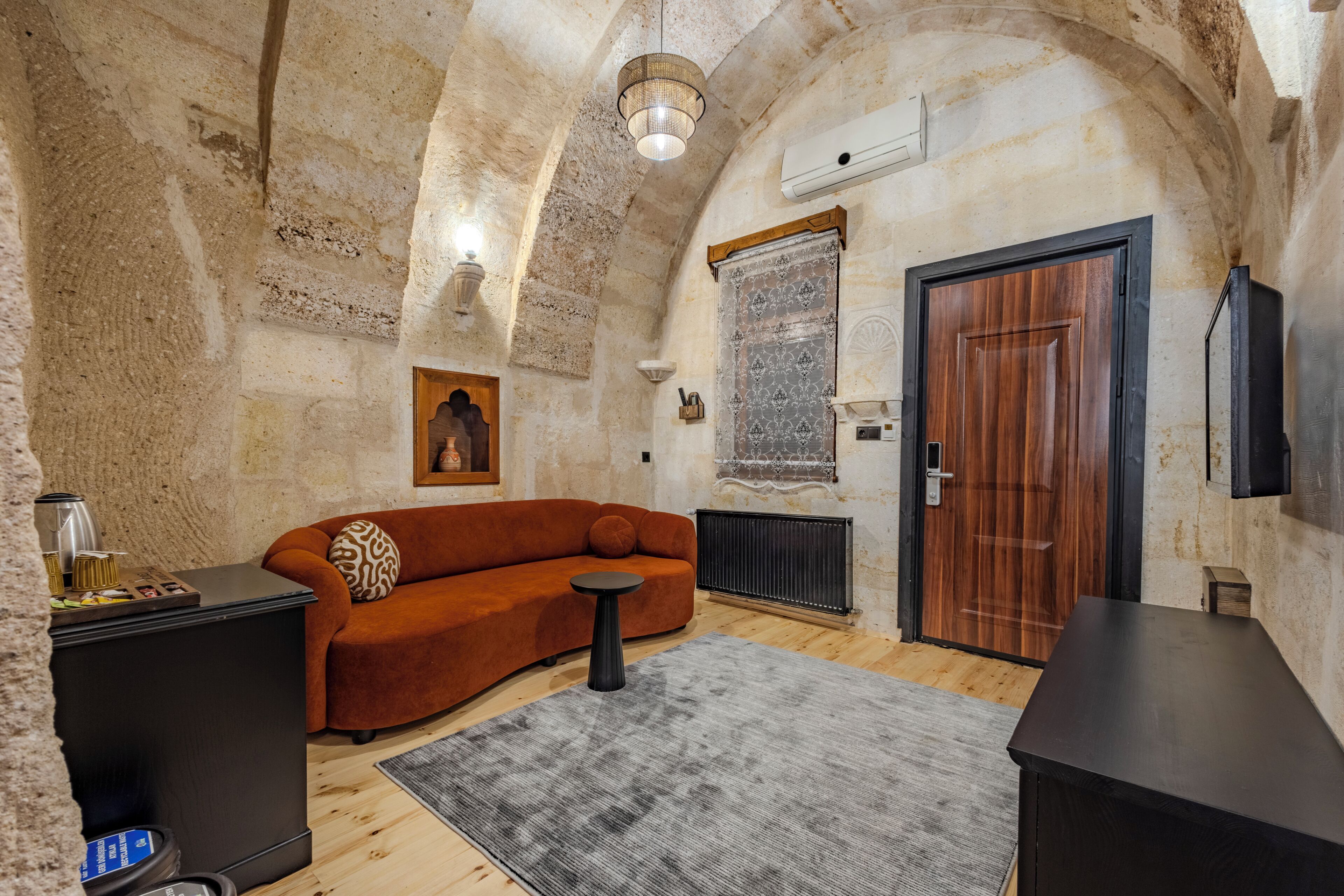Una habitación con pared de piedra, puerta de madera, un sofá, una mesita y un radiador.